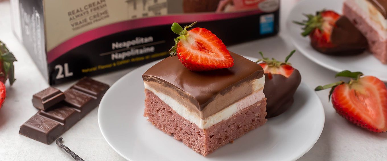 A perfect piece of Neapolitan Ice Cream garnished with chocolate strawberries on a white plate