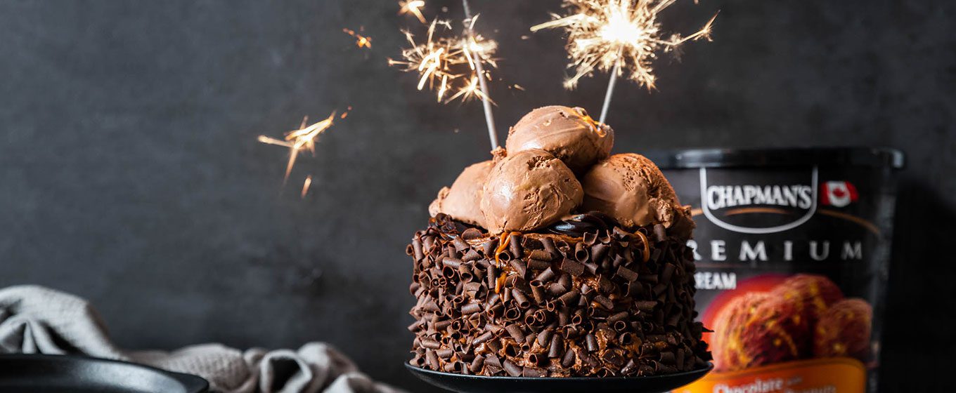 Chocolate Cake with Chocolate ice cream on top with lit sparklers with a dark grey background