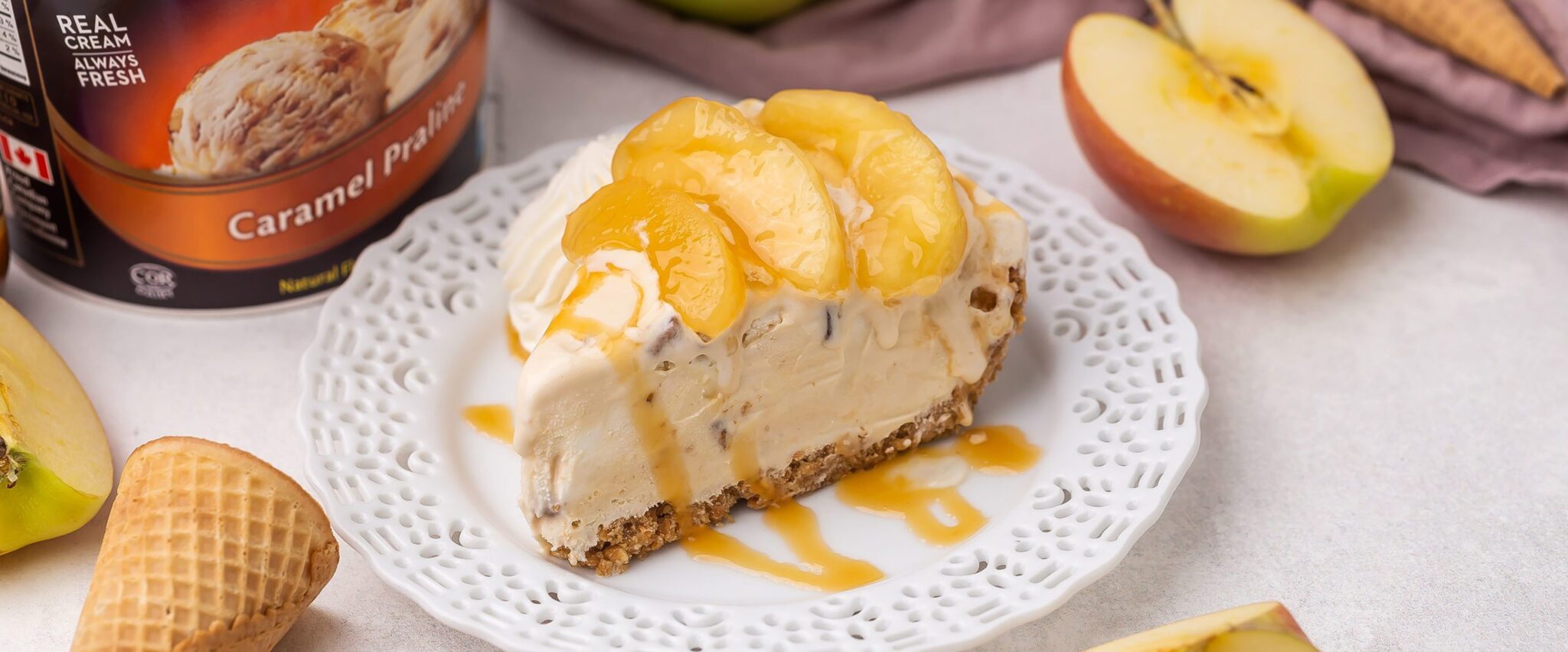 A slice of Caramel Apple Ice Cream Pie on a white decorative plate with a drizzle of caramel sauce on top.